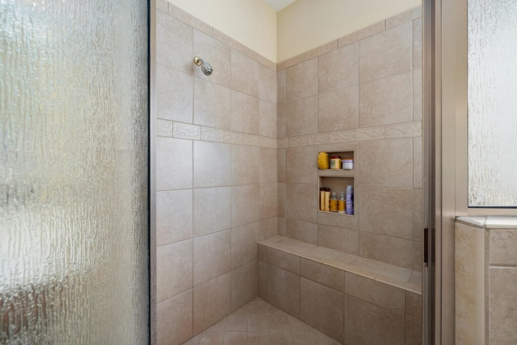 pexels-photo-12700514-12700514 Elegant walk-in shower with beige tiles and built-in shelves, perfect for a modern bathroom.